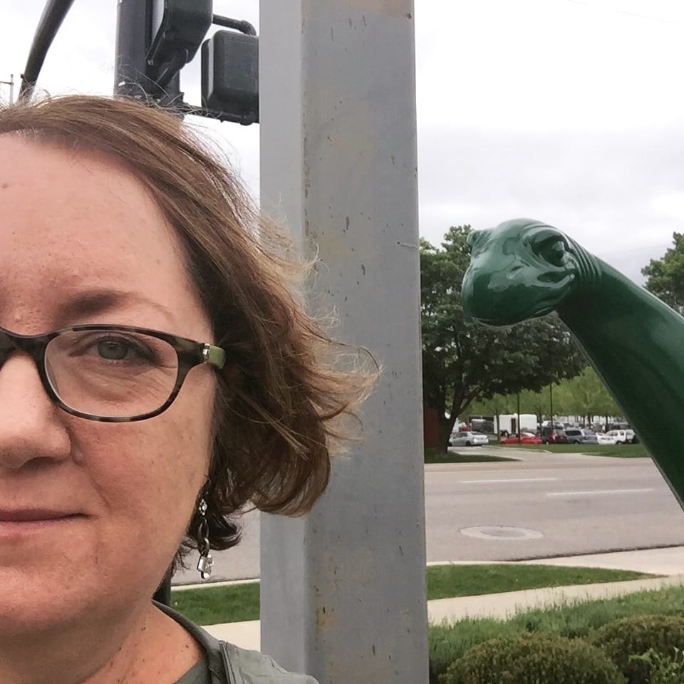 Nadya looks at the camera while a Sinclair gas station dinosaur watches.